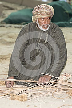 Omani man weaving palm leaves