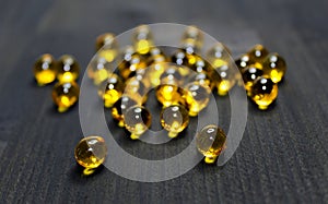 Omega 3-6-9 fish oil yellow round capsule round pills, linseed oil on wooden black background.