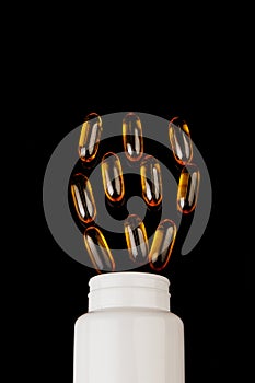 Omega-3 capsules on a black background. Health concept with fish oil capsules. White bottle