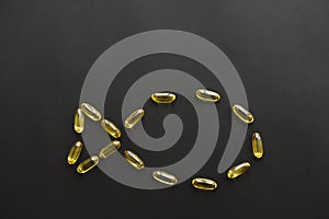 Omega 3 capsules in fish shape on black dark background. Fish oil pills. Top view. Dietary supplements. Health support and