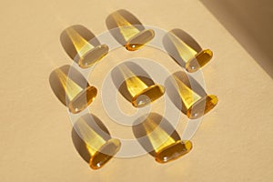 Omega 3 capsules lying and shadows on beige background. Fish oil in pills