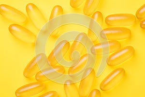 Omega 3 capsules on yellow background. Fish oil softgels. Supplement food vitamin D capsules. Top view