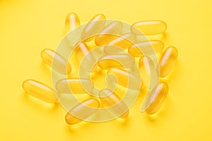 Omega 3 capsules on yellow background. Fish oil softgels. Supplement food vitamin D capsules. Top view