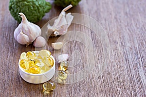 Omega 3 fish liver oil capsules and garlic on white background