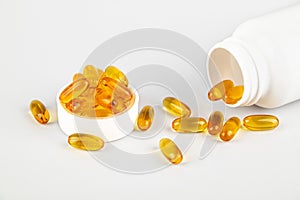 Omega 3 fish oil capsules spilling out of bottle on white background