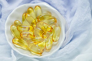 Omega 3 fish oil capsules in a white dish on a light background. Medical food supplies. Unsaturated fatty acid
