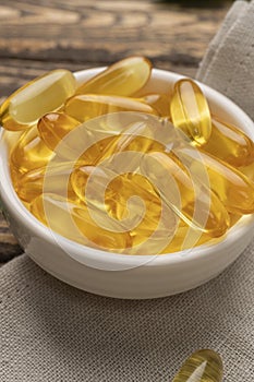 Omega 3. Gold fish oil gel Capsules in bowl isolated. Vitamin E