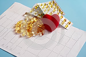 Omega-3 capsules lie on a cardiogram next to a red heart. Fish oil in tablets. Health support and heart treatment