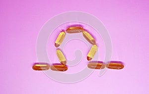 Omega 3 capsules - omega shape,  on pink background. Top view Health care vitamin concept