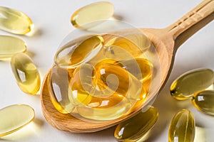 Omega 3 yellow capsules in wooden spoon on white background. EPA and DHA are two types of Omega-3 fats Essential Fatty photo