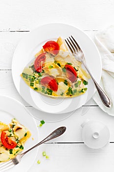 Omelet. Eggs fried. Scrambled eggs with green onion and fresh tomato. Omlette on white plate. Breakfast. Top view