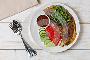 Omelet with mussels. Popular Thai food served with fresh vegetables and sauce on a plate. The view from the top. Copy-space.