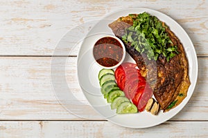 Omelet with mussels. Popular Thai food served with fresh vegetables and sauce on a plate. The view from the top. Copy-space.