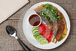 Omelet with mussels. Popular Thai food served with fresh vegetables and sauce on a plate. The view from the top. Copy-space.