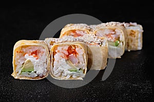Omelet sushi roll with avocado and flying fish roe inside on black background