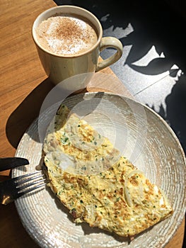Omelet with vegetables and bacon and coffee latte with cinnamon