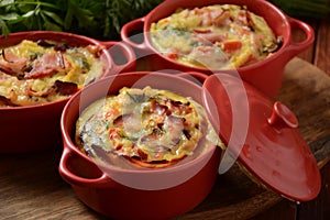 Omelette  with bacon, grated parmesan and greens in ceramic cocotte.
