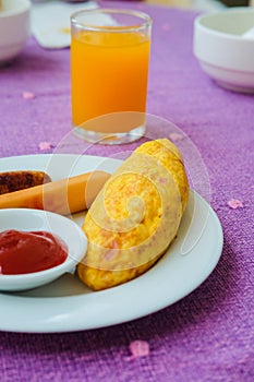 Omelette with bacon, sausage and oragne juice.