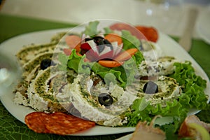 Omelette cheese roll combined with smoked sausage, sliced olives and lettuce salad on a plate with carrot