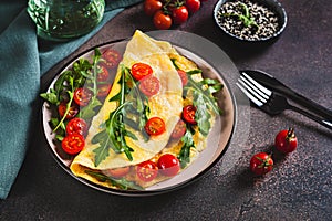 Omelette pancake with cherry tomatoes and arugula on a plate on the table