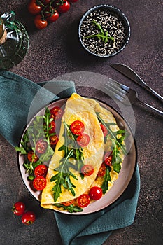 Omelette pancake with cherry tomatoes and arugula on a plate on the table top and vertical view