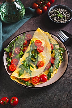 Omelette pancake with cherry tomatoes and arugula on a plate on the table vertical view