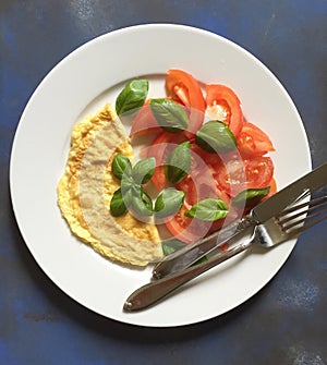 Omelette with tomato salad and basil leaves on plate