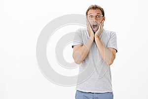 Omg awesome news. Portrait of impressed and amazed speechless emotive handsome guy in transparent glasses with bristle