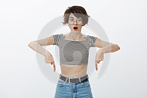 Omg, look down it is fantastic. Portrait of shocked and stunned girl in round glasses, dropping jaw while looking and