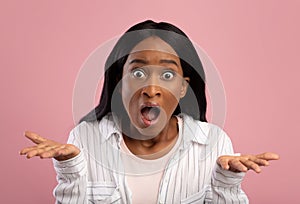 OMG. Millennial black woman emotionally reacting to shocking news, gesturing WTF on pink studio background