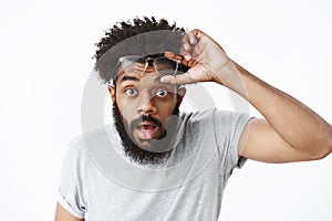 Omg unbelievable. Portrait of impressed and surprised handsome adult african american bearded guy taking off glasses