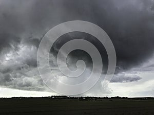 Ominous stormy sky with grey thunder cells and heavy rainfall on a town