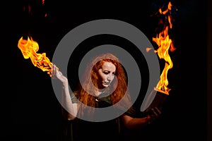 An ominous witch sets her spell book on fire with the power of thought. Red-haired woman conjures for Halloween. Flames