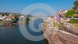 Omkareshwar cityscape, India, sacred hindu temple. Holy Narmada River, boats floating. Travel destination for tourists and pilgrim