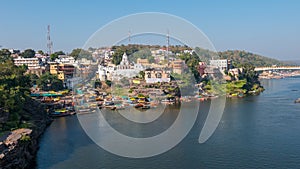 Omkareshwar cityscape, India, sacred hindu temple. Holy Narmada River, boats floating. Travel destination for tourists and pilgrim
