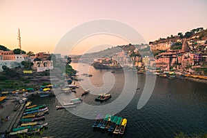 Omkareshwar cityscape, India, sacred hindu temple. Holy Narmada River, boats floating. Travel destination for tourists and pilgrim