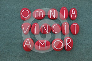 Omnia Vincit Amor, Love conquers all, latin phrase, Virgil poet, text composed with red colored stone letters over green sand