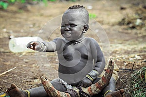 Omo River Valley, Ethiopia, November 2020, A small child from the Mursi tribe sits on the ground