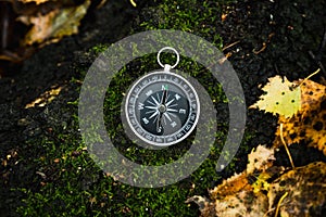 Ð¡ompass laying on the green moss in autumn forest. Shot from above. Autumn background