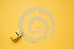 Omsk, Russia - May 26, 2019: Yellow retro toy car on yellow background. Valentines day.  Summer travel concept. Taxi. Top view.