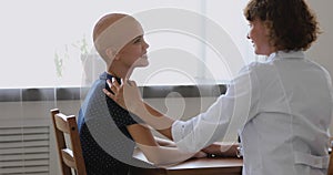 Oncologist doctor during conversation touch shoulder of bald cancer patient