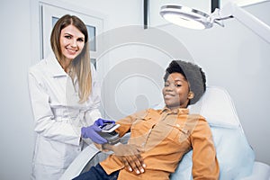 Oncology, skin cancer detection. Pleasant young woman, doctor dermatologist looking at camera with smile, while checking