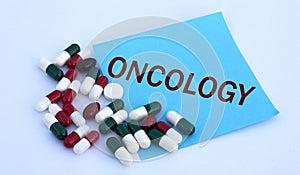 ONCOLOGY word on a blue sheet of paper against the background of multicolored tablets