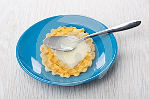 Ð¡ondensed milk and spoon on wafer cookie in blue saucer