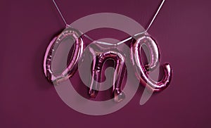 One 1 word metallic balloon on the purple wall background.