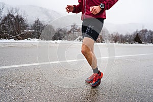 One adult caucasian man running in winter day male athlete runner training on the open road in nature with snow health and fitness