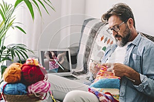 One adult man at home follow online knit tutorial to relax and enjoy resting home leisure activity sitting on the sofa - male