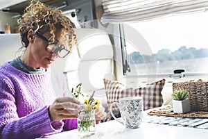 One adult woman caring plants and flowers inside a camper van modern tiny house motorhome rv alone. People living vanlife fulltime photo