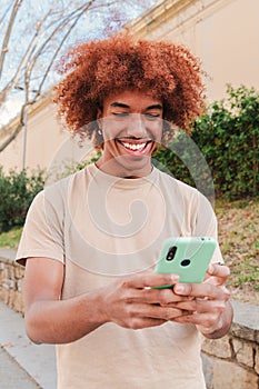 One african american teenager using a cellphone to send funny messages. Isolated happy young man smiling and having fun