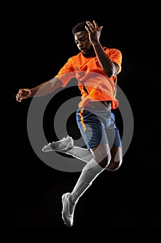 One African football soccer player playing isolated on black background. Concept of sport.